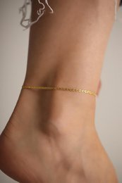  Delicate gold or silver anklet with a classic chain design, perfect for adding a touch of elegance to any outfit.