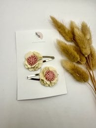 Set of 2 hair clips in silver and gold colors, featuring a bow design with pom-pom accents, suitable for kids' hairstyles.