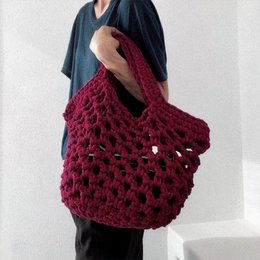 Burgundy crocheted shoulder bag with a roomy, open-weave design and sturdy handles.