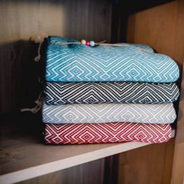 A stack of colorful, patterned towels in shades of blue, black, and red. The towels appear to be made of a soft, woven material and have a variety of geometric designs and patterns.