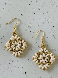  Elegant cream-colored statement earrings with a floral design in gold tones.
