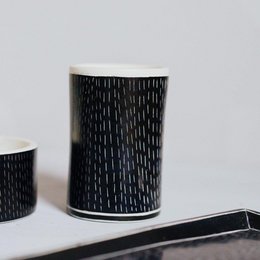 Tall black soapstone mug with geometric patterns including short lines, diamonds, zig zags, and triangles in a tribal style design.