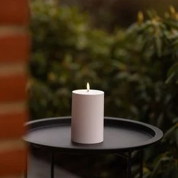 Tall, round, white pillar candle for outdoor use, made of wax and designed for illumination in an outdoor setting.