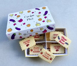 Box of personalized biscuits with the theme "Croque moi!" featuring a variety of colorful vegetable and food illustrations. Rectangular-shaped biscuits with the text "Mange mon biscuit" written on them.
