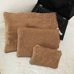  Toiletry bag in various sizes and colors including cream, taupe, rose, green, rust, and blue. Rectangular shape with soft, plush fabric.