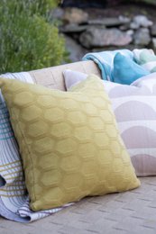 The pillow cover is made of soft, olive-colored cotton knit fabric with a hexagonal textured pattern. The material is durable and comfortable, making it suitable for use as a cushion cover.