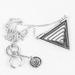 A small, triangular pendant necklace in oxidized silver, silver, or golden-plated metal, featuring a geometric design with a chain and additional charms.