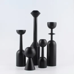 Tall, round black candle holders in various sizes, made of wood.