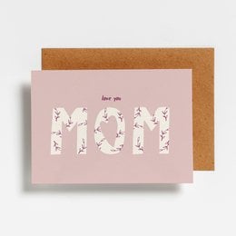 A pink greeting card with the text "Love you mom" in a floral pattern, accompanied by a brown envelope.