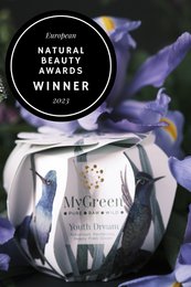 Youth Dream face treatment product, winner of Natural Health Awards 2023. Sleek glass bottle with silver label, surrounded by purple orchid flowers.