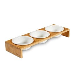 3 white ceramic pet food bowls on a wooden stand with 3 compartments. The bowls are labeled "CAMI" and the product is categorized as Food Bowls.