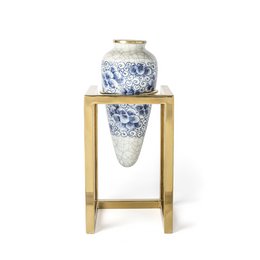 Tall, round blue and white ceramic vase with floral design, displayed on a gold metal stand.