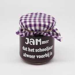 A small glass jar of jam with a purple and white checkered fabric lid. The label on the jar reads "JAMmer that the school year is already over".