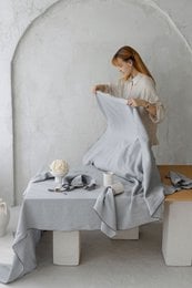 Off-white linen tablecloth, 250x145 cm, with a minimalist floral centerpiece arrangement on a white table.