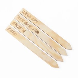 Wooden vegetable labels with humorous text, including "Grow with the flow", "Little prick", "The plant and I need a drink", and "Please don't die". These labels are made of wood and feature laser-etched text.