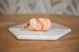 Velvy marble poop bag holder, made of marble material, rectangular shape, orange and white color pattern.