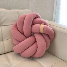 Soft, plush knot cushion in a rose color. Decorative accent pillow with a unique knotted design.