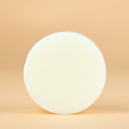 Coconut-scented conditioner bar with a round, solid shape.
