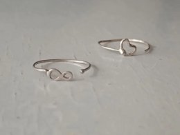  Two silver stacking rings with heart and infinity symbols.