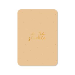  Greeting card with gold foil text that says "Strength". The card is made of a beige-colored material and has a simple, minimalist design.