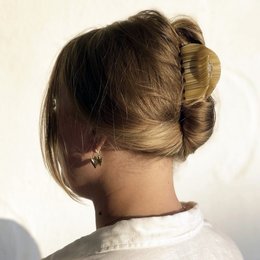 A sandy beach-inspired claw clip with a textured, wavy design in a light beige color.