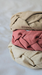 Braided linen headband in neutral colors including camel, creme, sand, and dusty pink. Soft, textured material suitable for kids.