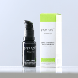 A detox eye cream in a black bottle with a green and white label. The cream is designed to reduce the appearance of dark circles and puffiness around the eyes.