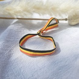 Woven bracelet in the colors of the German flag, featuring a braided design with orange, black, and yellow stripes.