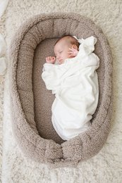 Cozy cream and taupe babynest with soft, plush fabric for newborn comfort and safety.