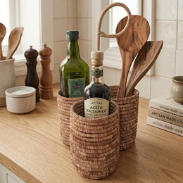  Woven rattan basket kitchen utensil holder, natural tan wicker, cylindrical shape, holds bottles and wooden spoons.