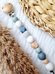 Pacifier clip with beads in shades of blue, gray, and white. Wooden and silicone beads in a variety of shapes and textures create a stylish and functional pacifier clip.