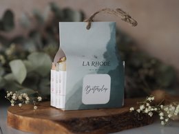A gift box with a light blue and white color scheme, featuring the text "La Roche" and "Bepante" on the packaging. The box is placed on a wooden surface with some floral accents.