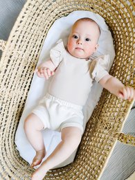 Beige ribbed bodysuit with ruffled short sleeves, suitable for infants and toddlers.