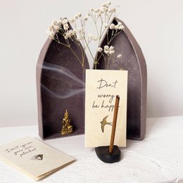 Off-white and taupe pocket altar with a hummingbird design, featuring a candle, crystals, and a note.