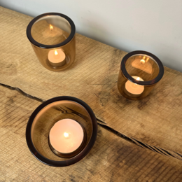  Round, medium-sized amber glass tea light holders with black rims.