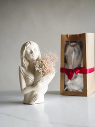  Elegant white ceramic vase in a minimalist design, available in two color variants - white and sand. The vase features a simple, abstract human figure holding a bouquet of dried flowers, creating a serene and artistic display.