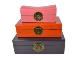 Set of 3 decorative boxes in various colors and shapes, featuring brass-colored metal accents and clasps. The boxes appear to be made of wood or a similar material, with a textured or patterned surface. The boxes are stacked, creating an interesting visual display.