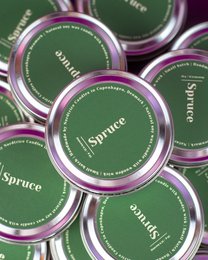 Medium-sized, spruce-scented soy candles in green containers.