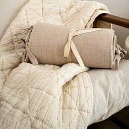  Beige quilted bedding set with decorative pillows, featuring a neutral color scheme and textured fabric for a cozy, rustic bedroom decor.
