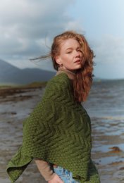 Cozy green aran poncho with cable knit pattern, perfect for cool weather.