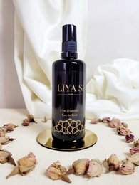 Rose water cream in a dark glass bottle with a floral design. The product is called "The inestimable Rose Water" and is part of the Liyas brand.