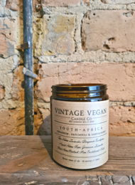 Vintage vegan travel candle with scents of geranium, patchouli, and sandalwood. Cylindrical glass container with label.