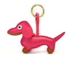 Keychain in the shape of a pink and gold dachshund dog. The keychain has a round gold ring at the top for attaching to keys or a bag.
