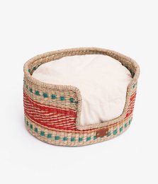 Oval-shaped pet basket made of woven natural materials in a multicolor pattern, with a removable cushion. Suitable for small to medium-sized pets.