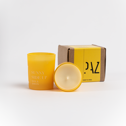 Sunny Side Up Scented Candle, lemon and basil scented, round tall candle in yellow packaging.