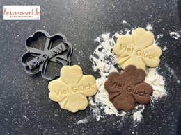 Shamrock-shaped cookie cutters in black and brown, with "Good Luck" text imprinted on the cookies. Suitable for baking and decorating St. Patrick's Day treats.
