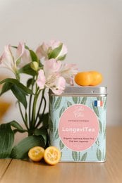 Organic green tea in a floral-patterned box. The tea leaves are displayed in a ceramic flower-shaped container, showcasing the natural, high-quality product.