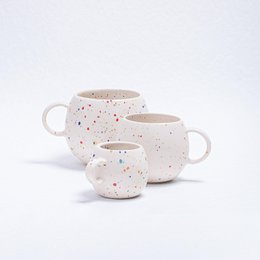  A white ceramic mug with a speckled pattern, featuring a round, tall shape and a handle. The mug is suitable for parties and events.