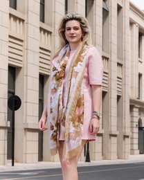  Soft, floral-patterned scarf in shades of brown, beige, and pink. Made of lightweight, flowing fabric for a stylish accessory.