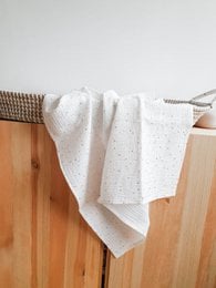 Soft, cozy cotton swaddle blanket in a delicate gold dot pattern.